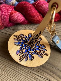 a pair of scissors and some yarn on a wooden table next to a piece of wood