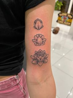 a woman's arm with three lotus tattoos on the left side of her body