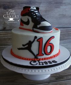 a cake that has a shoe on top and the number 16 is decorated with red, black, and white icing