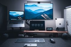 a desk with two monitors, keyboard and mouse on it in front of a laptop