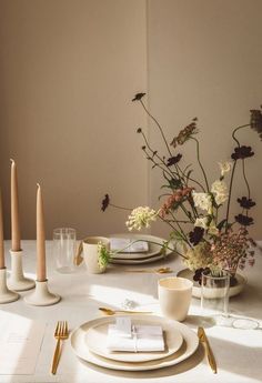 the table is set with plates, silverware and flowers