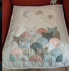 a cat themed baby quilt on a red chair