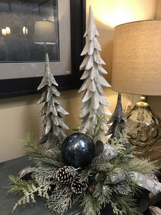 a christmas centerpiece with pine cones, evergreens and silver ornaments on a table