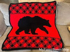 a crocheted bear on a red and black afghan sits on a couch next to a teddy bear