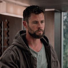 a man with a beard standing in front of a window