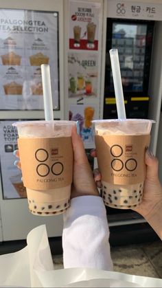 two people are holding up their drinks in front of a vending machine at a fast food restaurant