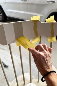 a person is painting the side of a white chair with yellow tape on it's sides