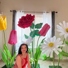 a woman sitting on the ground in front of fake flowers