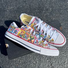 a pair of sneakers with comic covers on them sitting on the ground next to a skateboard