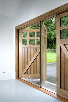 an open wooden door in front of a white wall and green field behind the doors