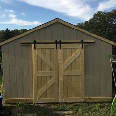 an outdoor storage shed with two sliding doors on the front and one open door on the side