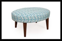 a blue and white ottoman sitting on top of a wooden leg stool with an upholstered design