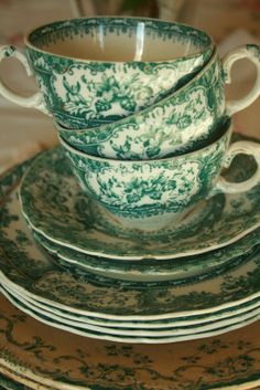 a stack of green and white teacups sitting on top of eachother