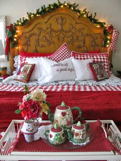 a cat is laying on a bed with red and white sheets, plaid pillows, and christmas decorations