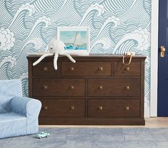 a blue chair sits in front of a dresser with a white stuffed animal on it