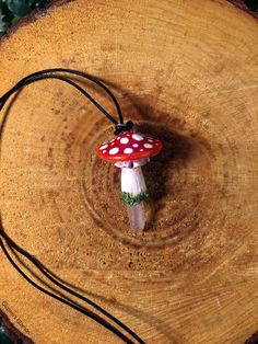 a small mushroom sitting on top of a tree stump next to a black cord and green leaves