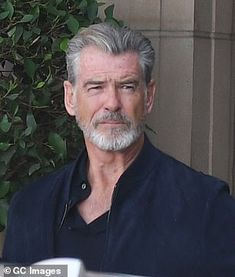 an older man with grey hair and beard sitting outside