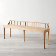 a wooden bench sitting on top of a hard wood floor next to a white wall