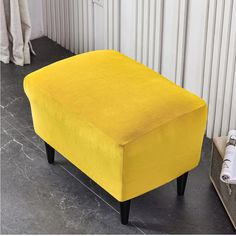 a yellow footstool sitting on top of a floor next to a white wall