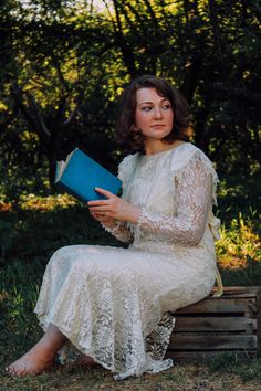 a woman sitting on a wooden bench holding a book