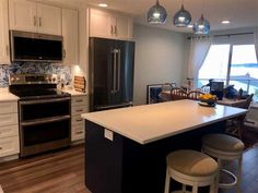 a kitchen with an island, refrigerator and stove top oven next to a dining room table