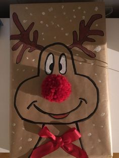 a paper bag with a reindeer face on it and a red pom - pom