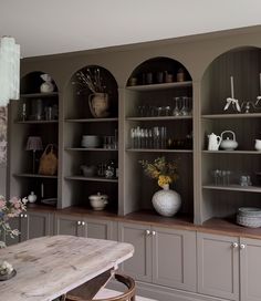 a dining room table and some shelves with vases