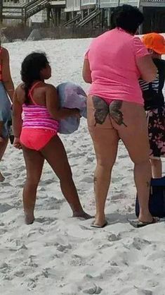 three women in bathing suits on the beach with their backs to each other and luggage behind them