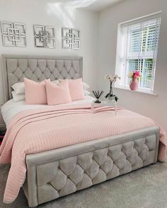 a bed with pink pillows and blankets in a bedroom