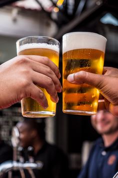 two men toasting with beer glasses in front of them