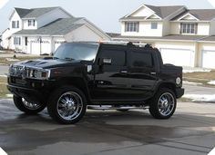 a black hummer is parked in front of some houses