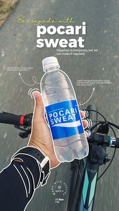 a person holding a water bottle while riding a bike