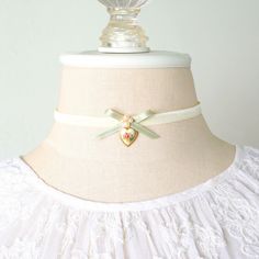 This charming choker necklace is handmade with a soft off white double sided velvet ribbon. It features a delicate sage green silk satin ribbon bow, pearl beads and a rare vintage Limoge heart charm in a brass frame with a sweet floral posy design. See photos showing coordinating designs with varying bows and colors, available separately in the Rosy Posy Designs shop. * Size ~ Adjustable length 12 - 15 inches with extender chain    Please check your neck size carefully as I do not accept returns Elegant Heart Choker As Gift, Elegant Heart Charm Choker As A Gift, Delicate Adjustable Choker For Gift, Handmade Delicate Choker For Gifts, Cream Dainty Jewelry For Gifts, Cream Dainty Jewelry As Gift, Cream Dainty Jewelry Gift, Delicate Cream Jewelry As A Gift, Dainty Cream Jewelry Gift