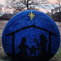 a large blue ball with some people on it in the middle of a field next to a fence