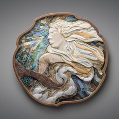 a decorative plate with a woman's face and wavy hair on the side, inlaid to wood