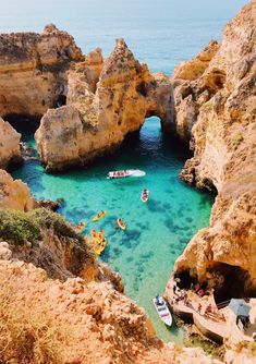 boats are in the clear blue water near rocky cliffs