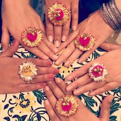 several women's hands with different colored rings on top of each other, all holding their fingers together