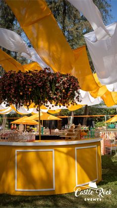 an outdoor bar with lots of yellow umbrellas and flowers hanging from it's roof