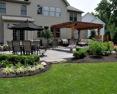 a patio with an umbrella and chairs next to a large house in the back yard