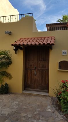 an entrance to a yellow building with a brown door and red tile on the roof