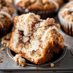 a muffin with white frosting and cinnamon crumbs on top is cut in half