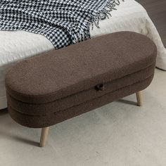 a bed with a brown footstool sitting on top of it