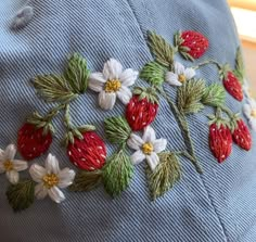 a blue hat with strawberries and daisies embroidered on it