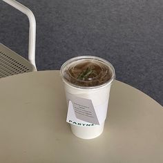 a cup of coffee sitting on top of a table next to a white plastic chair