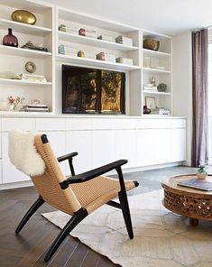 a living room filled with lots of furniture and bookshelves next to a window