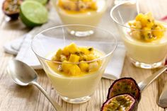 three desserts with fruit in small bowls on a wooden table next to spoons