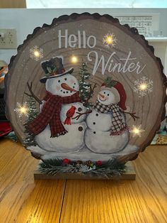 two snowmen are standing next to each other in front of a sign that says hello winter