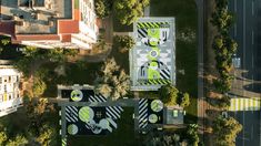 an aerial view of some buildings in the middle of a city with trees and grass