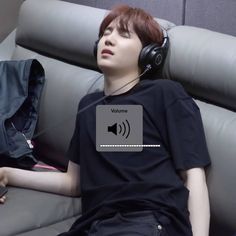 a man laying on top of a gray couch wearing headphones and listening to music