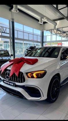 a white mercedes car with a red bow on it's hood in a showroom